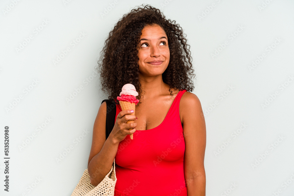 Young brazilian woman going to the beach holding an ice cream isolated on blue background dreaming of achieving goals and purposes Young brazilian woman going to the beach holding an ice cream isolated on blue background dreaming of achieving goals and purposes