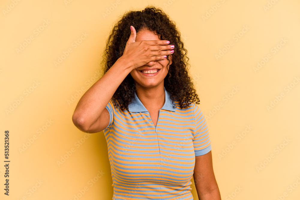 Young Brazilian woman isolated on yellow background covers eyes with hands, smiles broadly waiting for a surprise. Young Brazilian woman isolated on yellow background covers eyes with hands, smiles broadly waiting for a surprise.