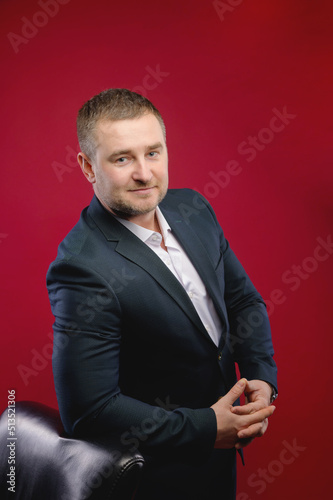 Portrait of a handsome man in an elegant suit on a red background. Studio shot. looking thoughtfully into the camera