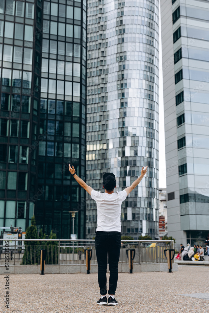 Fototapeta premium Stylish young man admires the large glass skyscrapers. Feels like a businessman. Business and man concept between skyscrapers.