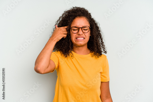Young Brazilian woman isolated on blue background covering ears with hands. © Asier