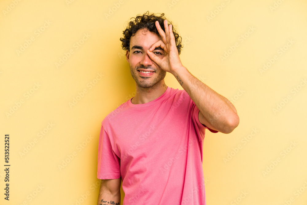 Young caucasian man isolated on yellow background excited keeping ok gesture on eye.