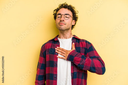 Young caucasian man isolated on yellow background taking an oath, putting hand on chest.