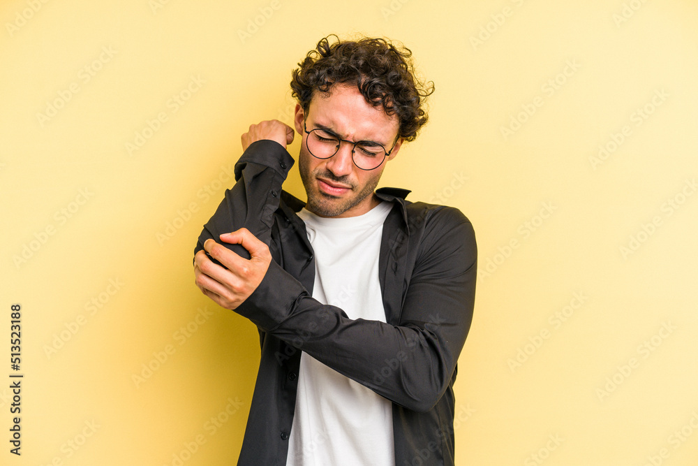 Naklejka premium Young caucasian man isolated on yellow background having a neck pain due to stress, massaging and touching it with hand.