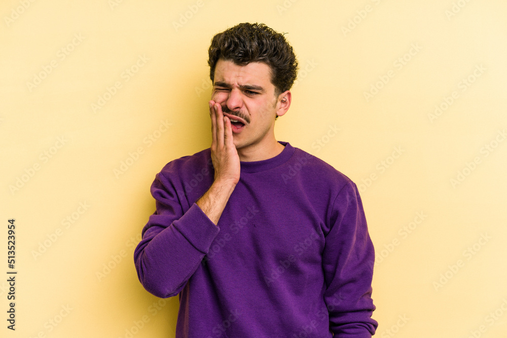 Young caucasian man isolated on yellow background yawning showing a tired gesture covering mouth with hand. Young caucasian man isolated on yellow background yawning showing a tired gesture covering mouth with hand.