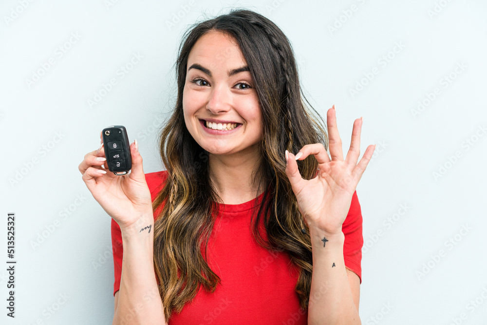 Young caucasian woman holding car keys isolated on blue background cheerful and confident showing ok gesture. Young caucasian woman holding car keys isolated on blue background cheerful and confident showing ok gesture.