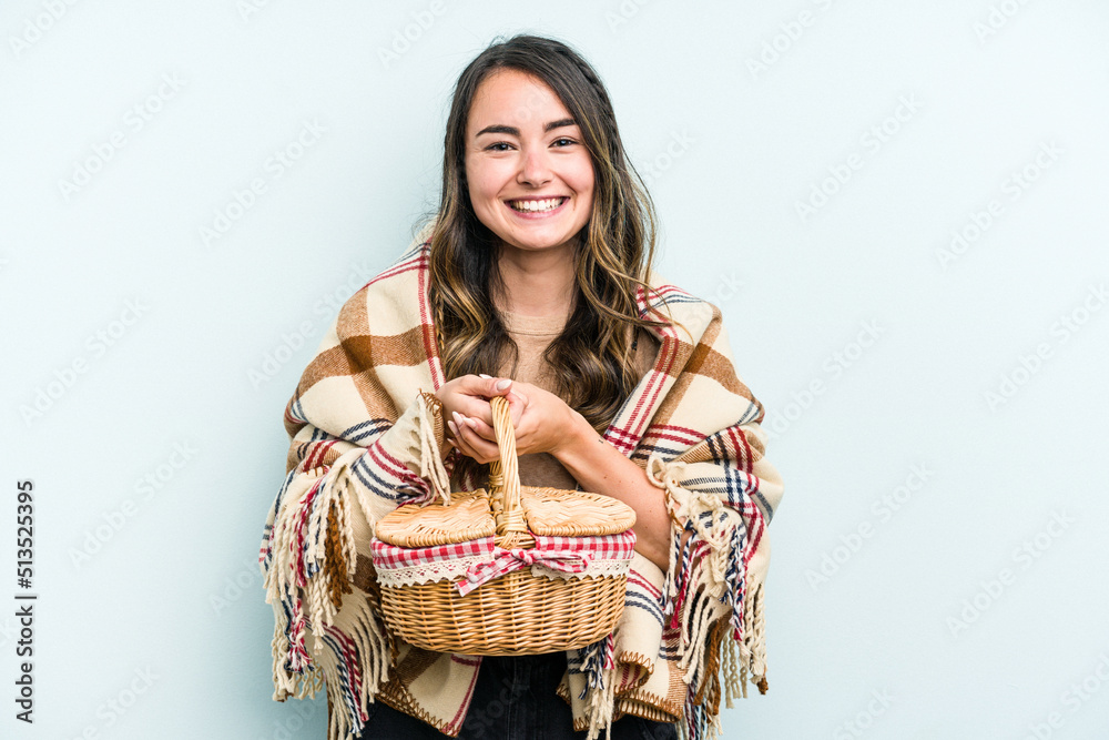 Young caucasian woman holding a picnic basket isolated on blue background happy, smiling and cheerful. Young caucasian woman holding a picnic basket isolated on blue background happy, smiling and cheerful.