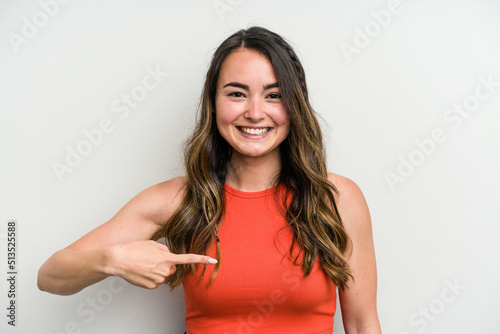 Young caucasian woman isolated on white background person pointing by hand to a shirt copy space  proud and confident