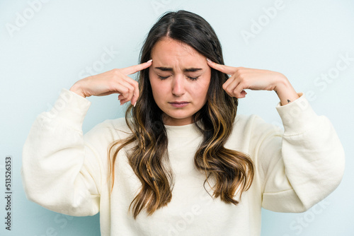 Young caucasian woman isolated on blue background focused on a task, keeping forefingers pointing head.