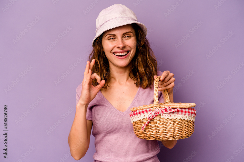 Young caucasian woman going on a picnic isolated on purple background cheerful and confident showing ok gesture.