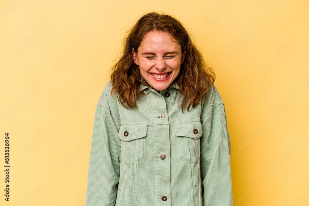 Young caucasian woman isolated on yellow background laughs and closes eyes, feels relaxed and happy. Young caucasian woman isolated on yellow background laughs and closes eyes, feels relaxed and happy.