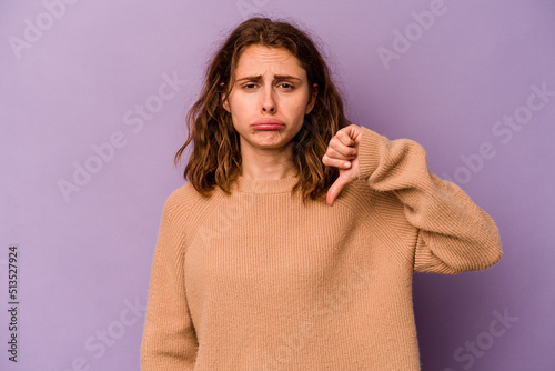 Young caucasian woman isolated on purple background showing a dislike gesture, thumbs down. Disagreement concept.