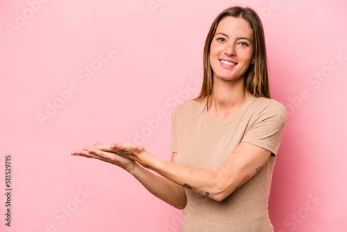 Young caucasian pregnant woman isolated on white background holding a copy space on a palm. © Asier