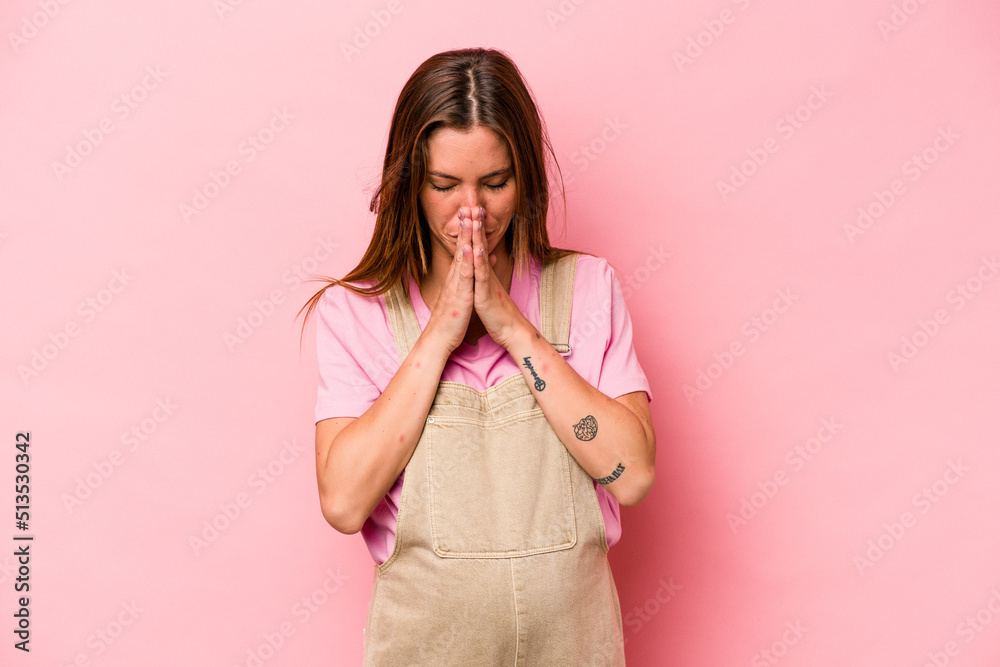Young caucasian pregnant woman isolated on white background praying, showing devotion, religious person looking for divine inspiration. Young caucasian pregnant woman isolated on white background praying, showing devotion, religious person looking for divine inspiration.