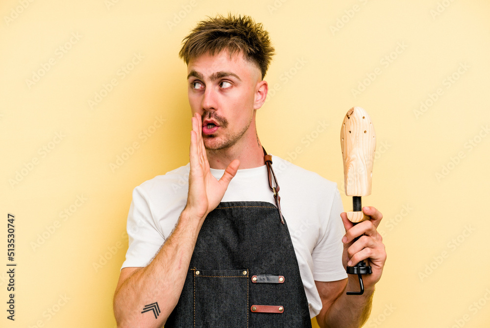 Young shoemarket man isolated on yellow background is saying a secret hot braking news and looking aside Young shoemarket man isolated on yellow background is saying a secret hot braking news and looking aside