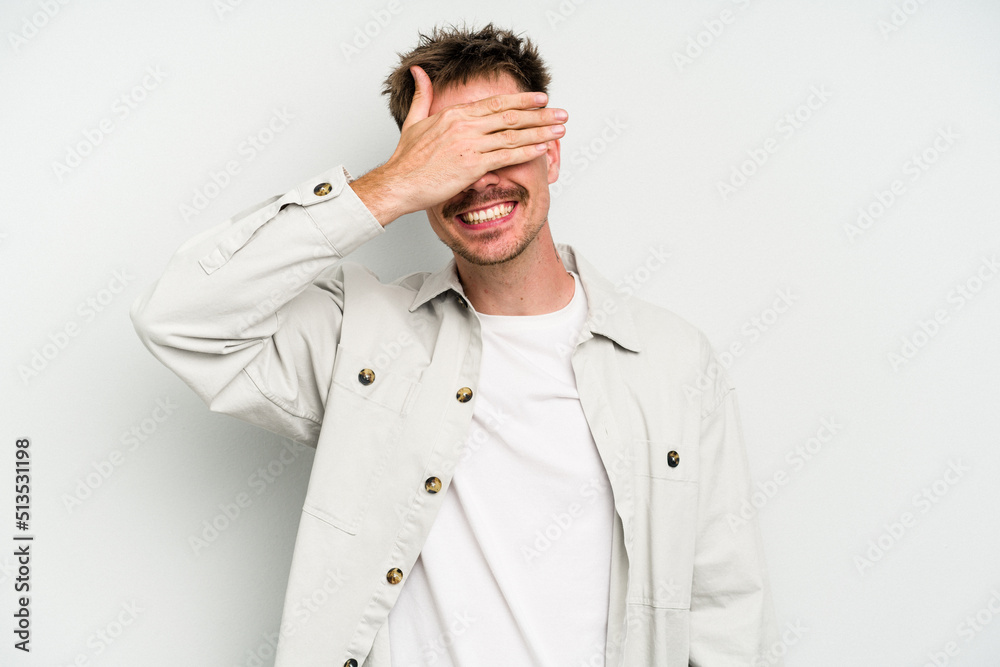 Young caucasian man isolated on white background covers eyes with hands, smiles broadly waiting for a surprise. Young caucasian man isolated on white background covers eyes with hands, smiles broadly waiting for a surprise.