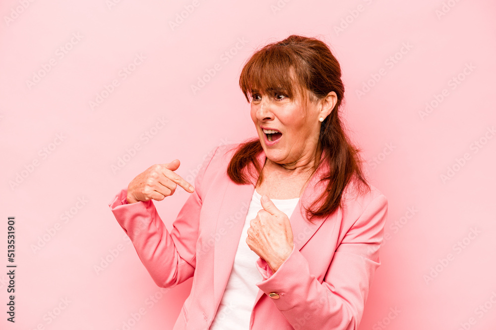 Middle age caucasian woman isolated on pink background surprised pointing with finger, smiling broadly. Middle age caucasian woman isolated on pink background surprised pointing with finger, smiling broadly.
