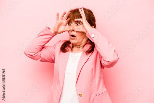 Foto Middle age caucasian woman isolated on pink background keeping eyes opened to find a success opportunity