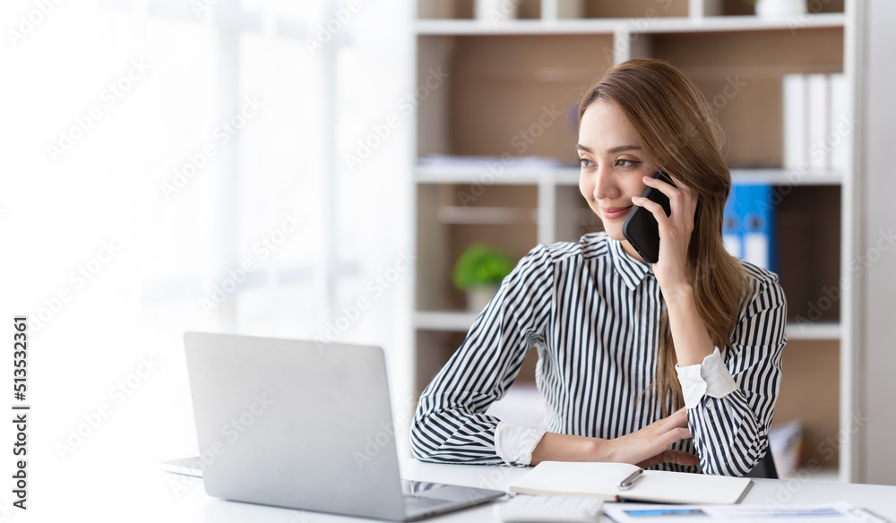 Young business woman on the phone at office. Business woman texting on the phone and working on laptop. Pretty young business woman sitting on workplace. Smiling business woman. Young business woman on the phone at office. Business woman texting on the phone and working on laptop. Pretty young business woman sitting on workplace. Smiling business woman.