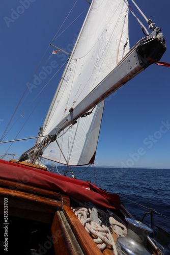 White Sailboat of the vessel floating on the sea with bright sun and blue sky