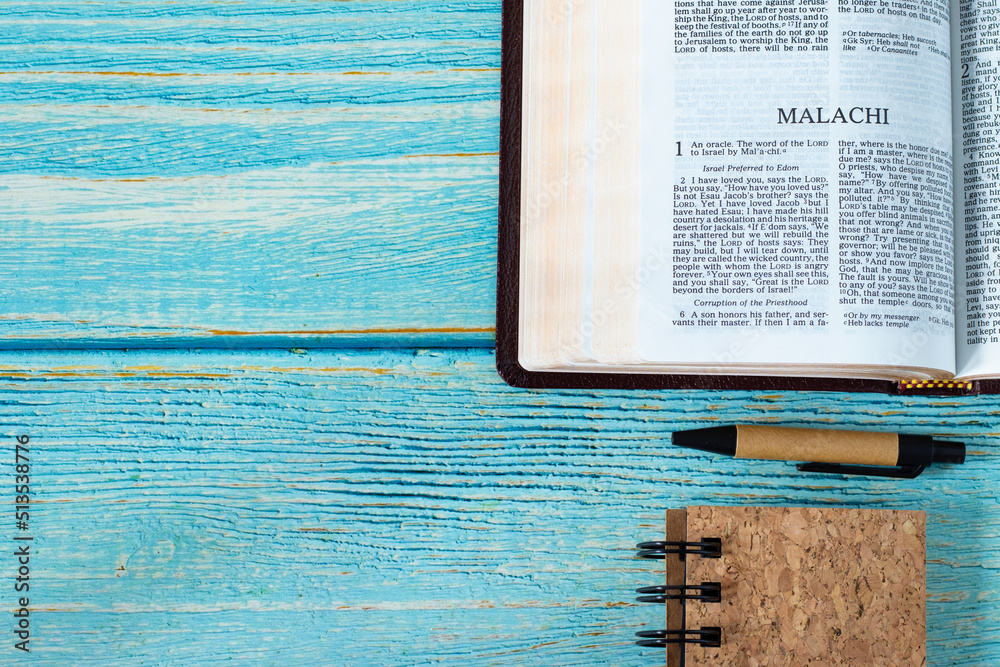 Malachi open Holy Bible Book on a rustic wooden table background with a ...