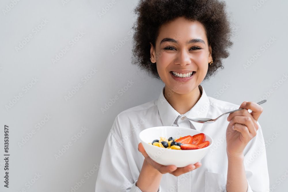 happy african american woman holding bowl with corn flakes and berries on white. happy african american woman holding bowl with corn flakes and berries on white.