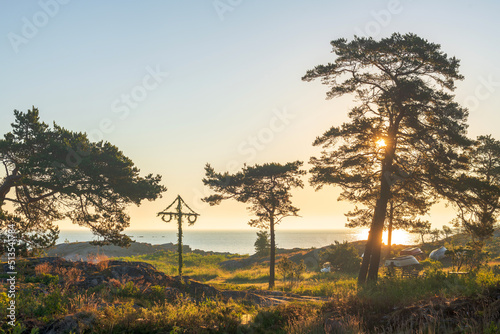 фотография Midsummer pole at the coastline during early morning with a warm clear sky