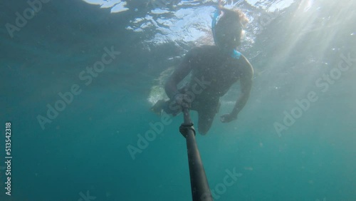 Wallpaper Mural silhouette of a man snorkeling and taking a selfie on a background of bright yellow sun shining from behind. Contrasting rays of the sun under the water illuminating the silhouette of a man immersed Torontodigital.ca