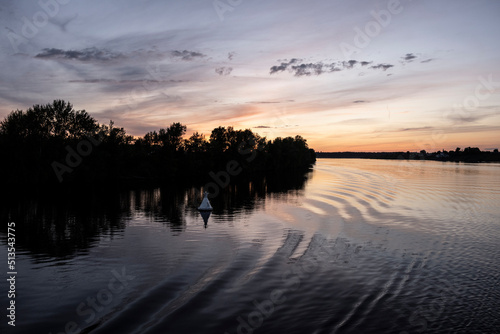 sunset on a large river with reflections in the water on a summer evening