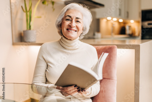 Mature woman smiling happily while reading a book