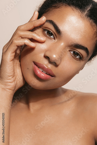 Vertical shot of beauty woman with perfect skin, applies daily care cream, moisturizer, brown background