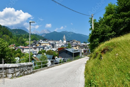 Scenic view of the town of Pieve di Cadore in Veneto region and Belluno province in Italy with a road leading towards the town and mountains in the Dolomitic Alps