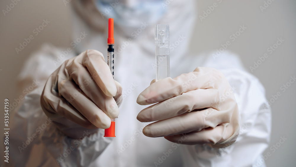 Isolated man in protective suit and gloves holding insulin syringe and ampoule with medication in hands close up. Vaccination against viral diseases. Immunization. Health care. Disease prevention Isolated man in protective suit and gloves holding insulin syringe and ampoule with medication in hands close up. Vaccination against viral diseases. Immunization. Health care. Disease prevention