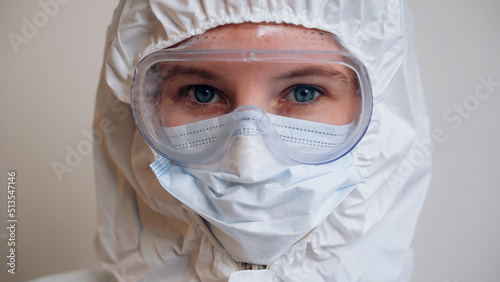 Eyes of tired medical worker close up. Doctor in protective mask and goggles. Outbreak of viral disease epidemic. Insulation. Coronavirus, monkeypox. Woman with blue eyes looks at camera and blinks