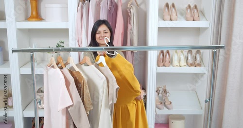 Young smiling woman seller hanging clothes from closet on mobile dressing room in store. Sale of the past collection.