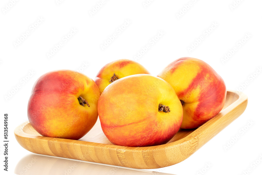 Several juicy organic nectarines on a wooden tray, close-up, isolated on a white background.