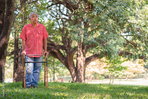 Happy old elderly Asian man uses a walker and walks in the Park.  Concept of happy retirement With care from a caregiver and Savings and senior health insurance