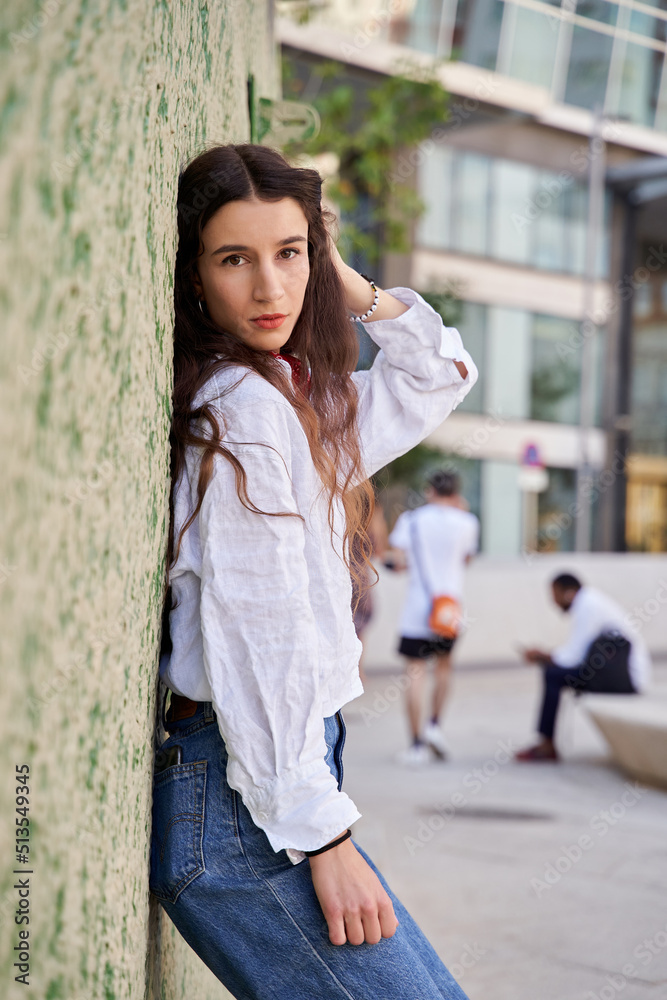 portrait of a young woman with long hair looking at the camera on a wall in green tones portrait of a young woman with long hair looking at the camera on a wall in green tones