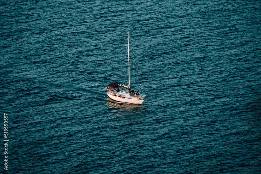 Fototapeta premium Boat floating in sea at sunset