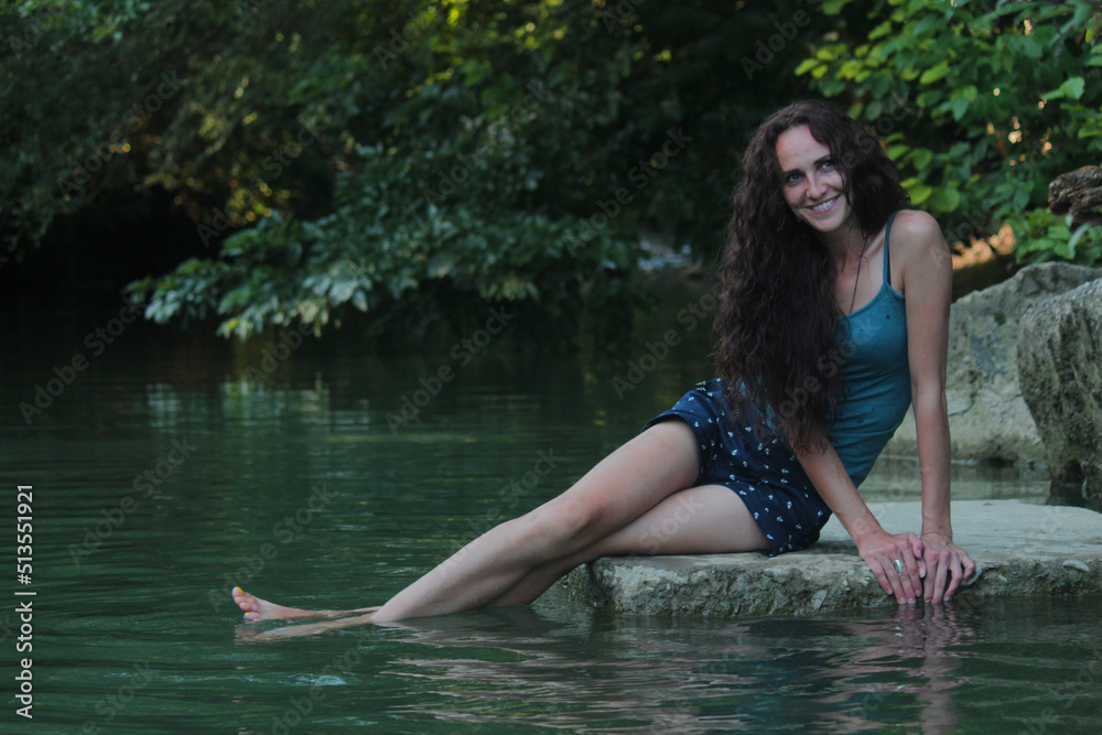 a girl with long hair is sitting by the river