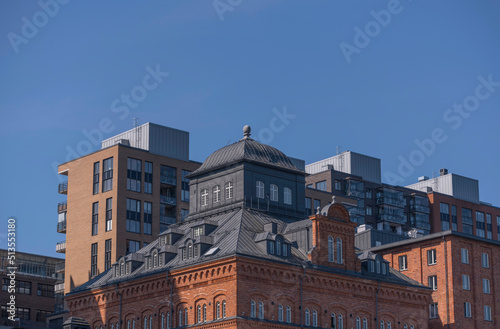 Roofs and facades of rebuilt old factory and new apartment buildings at the pier Kvarnholmen a sunny summer day in Stockholm
