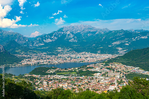 The city of lecco, shot from above, by day, with the surrounding mountains. 