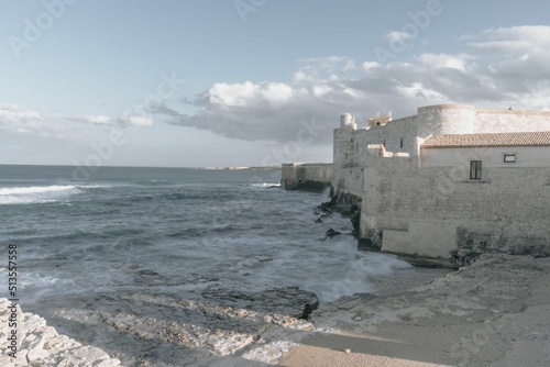 Beautiful landscape of a beach and a stone wall of a fort in Syracuse, Sicily