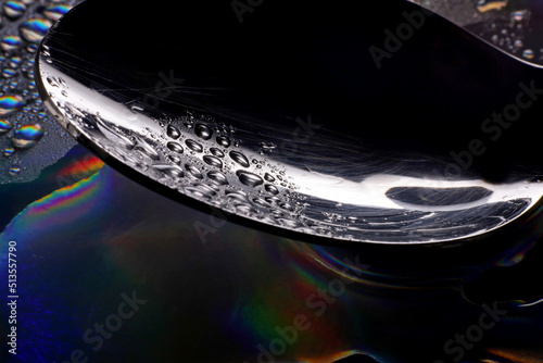 metal spoon with water drops on dark background 