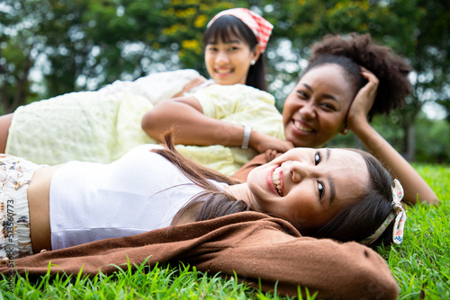 Smiling of diversity women laying on grass with bright smile in summer season at the park. Enjoy with nature and natural therapy