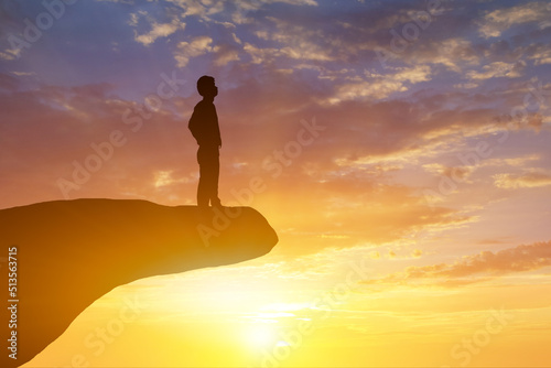 Silhouette of businessman look for the success on top mountain, sky and sun light background.