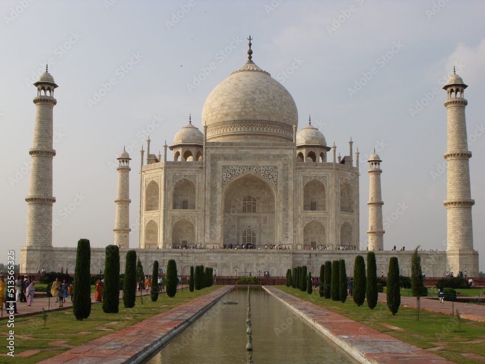 Taj Mahal, Agra, India, August 18, 2011: White marble mausoleum with four minarets seen from one of its fountains. Taj Mahal