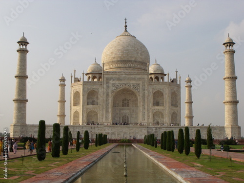 Taj Mahal, Agra, India, August 18, 2011: White marble mausoleum with four minarets seen from one of its fountains. Taj Mahal