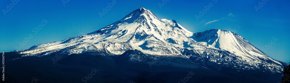 Panoramic view of a snowy mountain peak against a blue sky - obrazy, fototapety, plakaty 