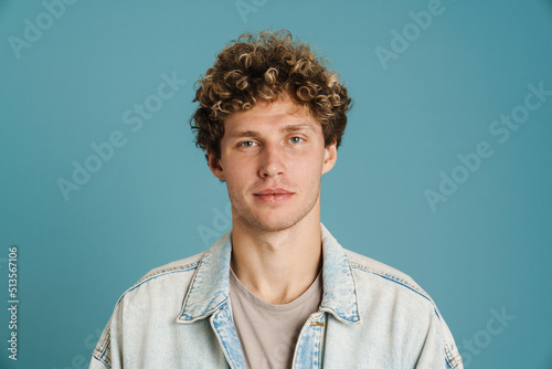 Young curly man wearing jacket posing and looking at camera